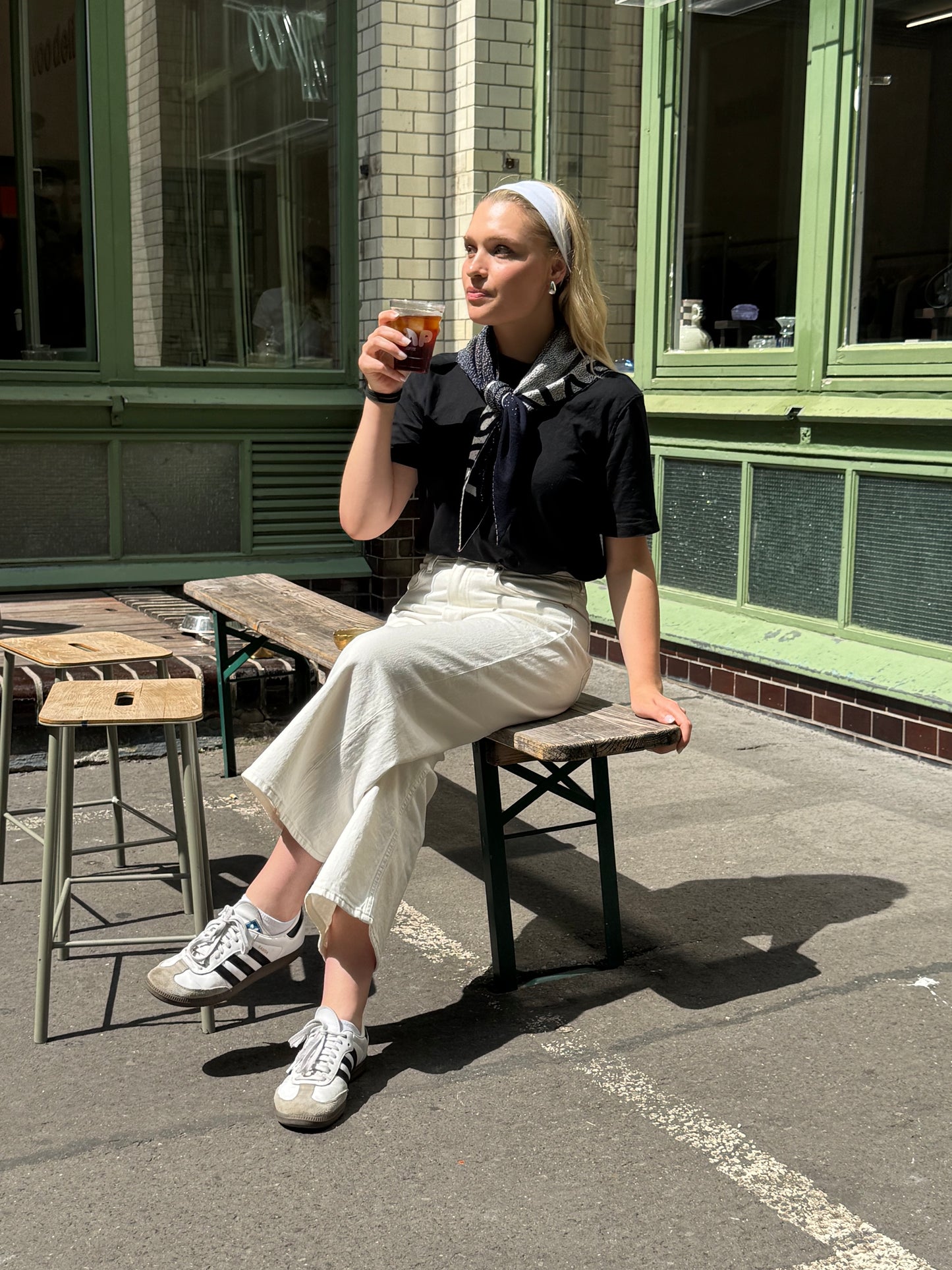 Woman wearing a scarf drinking coffee at a cafe